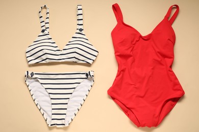 Two beautiful swimsuits on beige background, flat lay