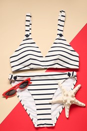 Striped swimsuit, sunglasses and starfish on color background, flat lay