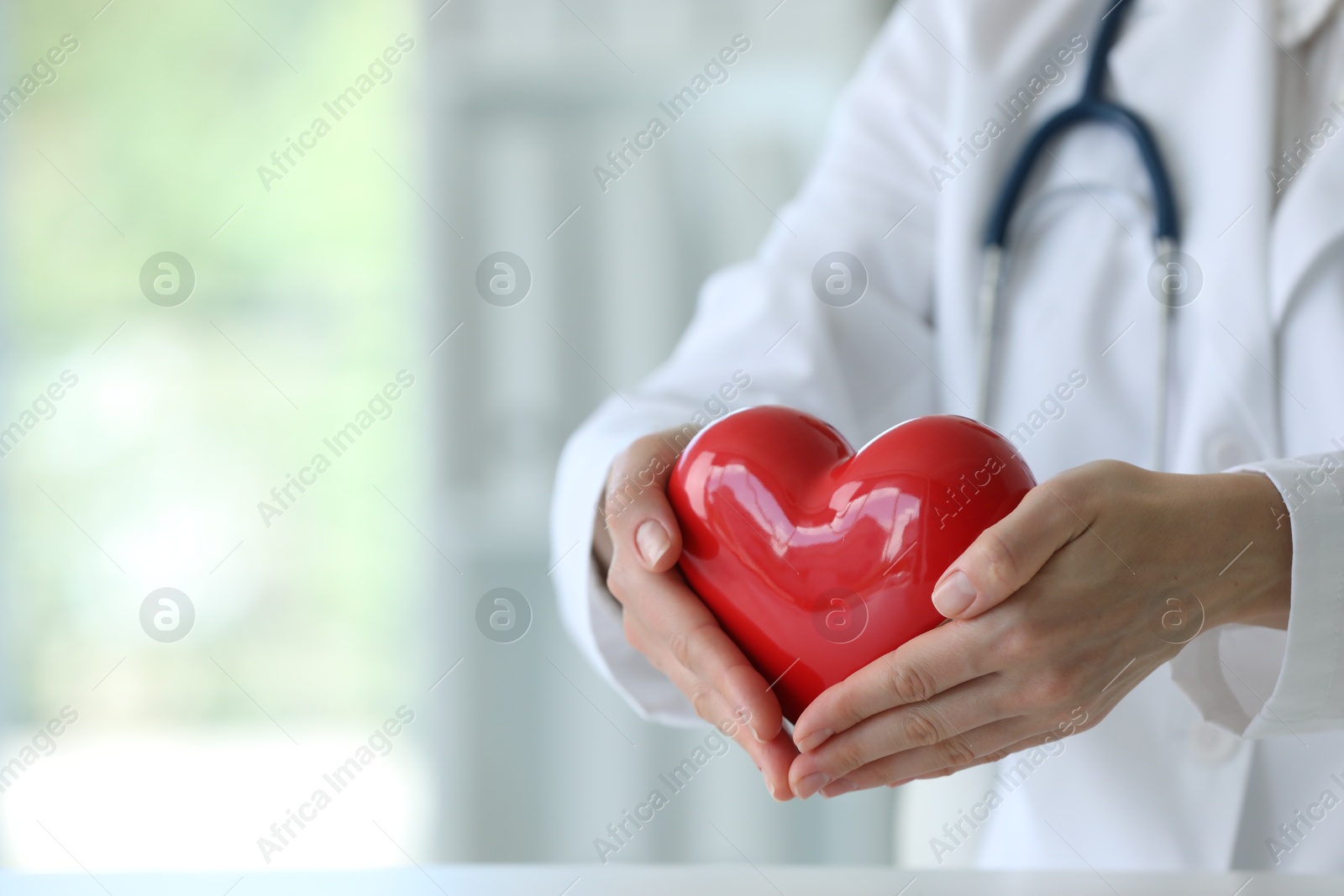 Photo of Doctor with red heart in clinic, closeup. Space for text