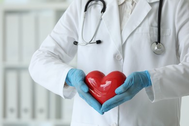 Photo of Doctor with red heart in clinic, closeup