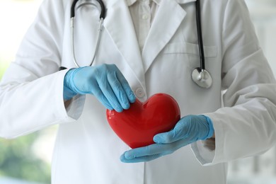 Photo of Doctor with red heart in clinic, closeup