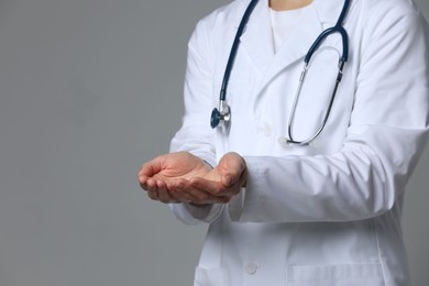 Photo of Doctor holding something on grey background, closeup. Space for text