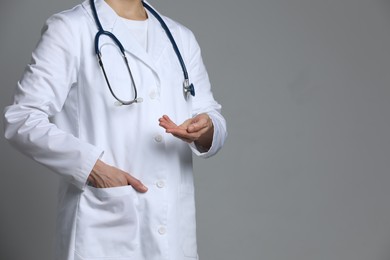Photo of Doctor holding something on grey background, closeup. Space for text