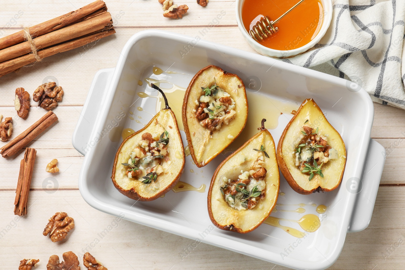 Photo of Tasty baked pears with nuts, blue cheese, thyme and honey in baking dish on wooden table, flat lay