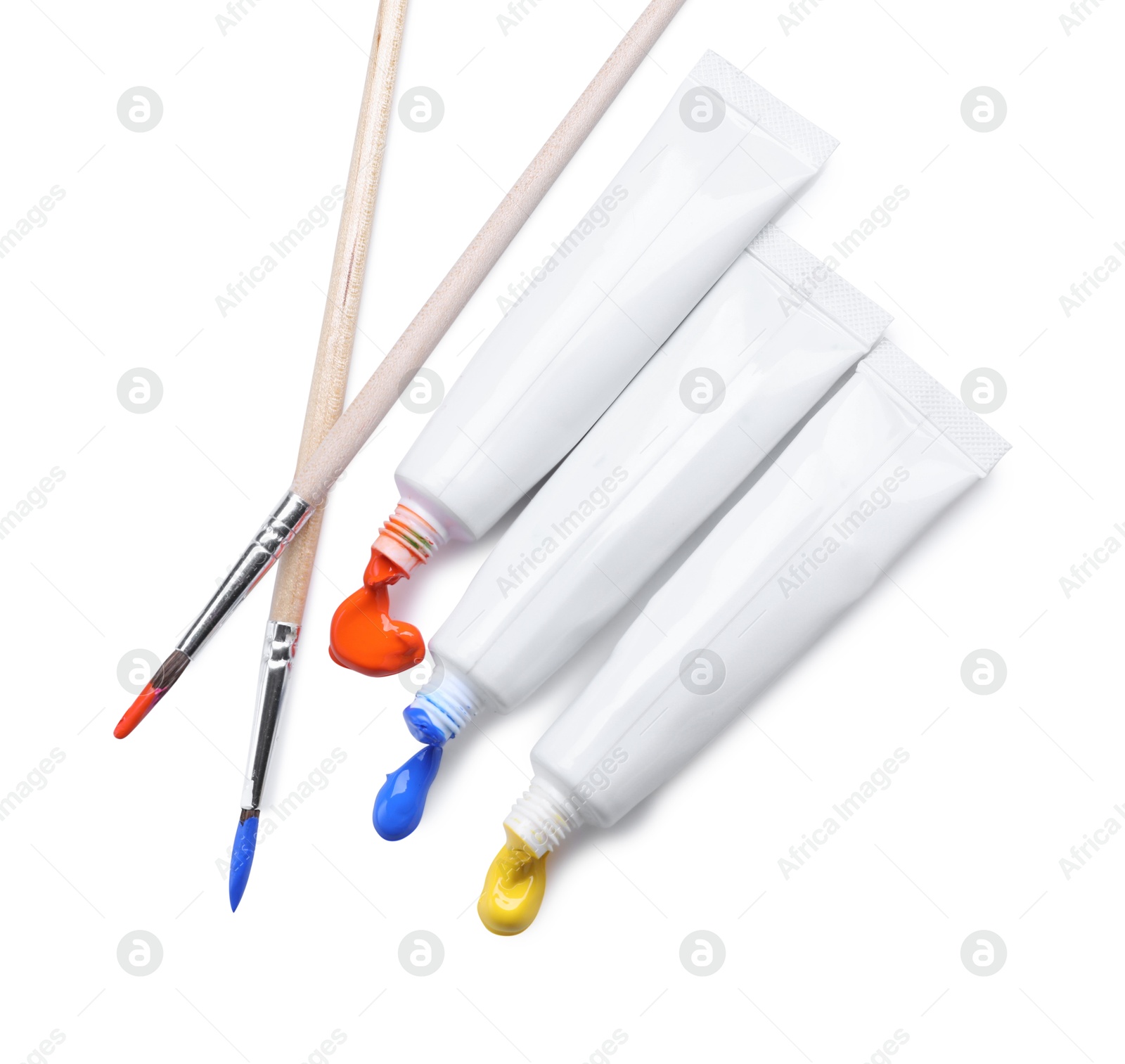 Photo of Tubes with colorful paints and brushes isolated on white, top view