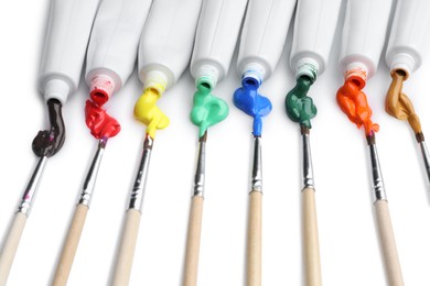 Photo of Tubes with colorful paints and brushes isolated on white