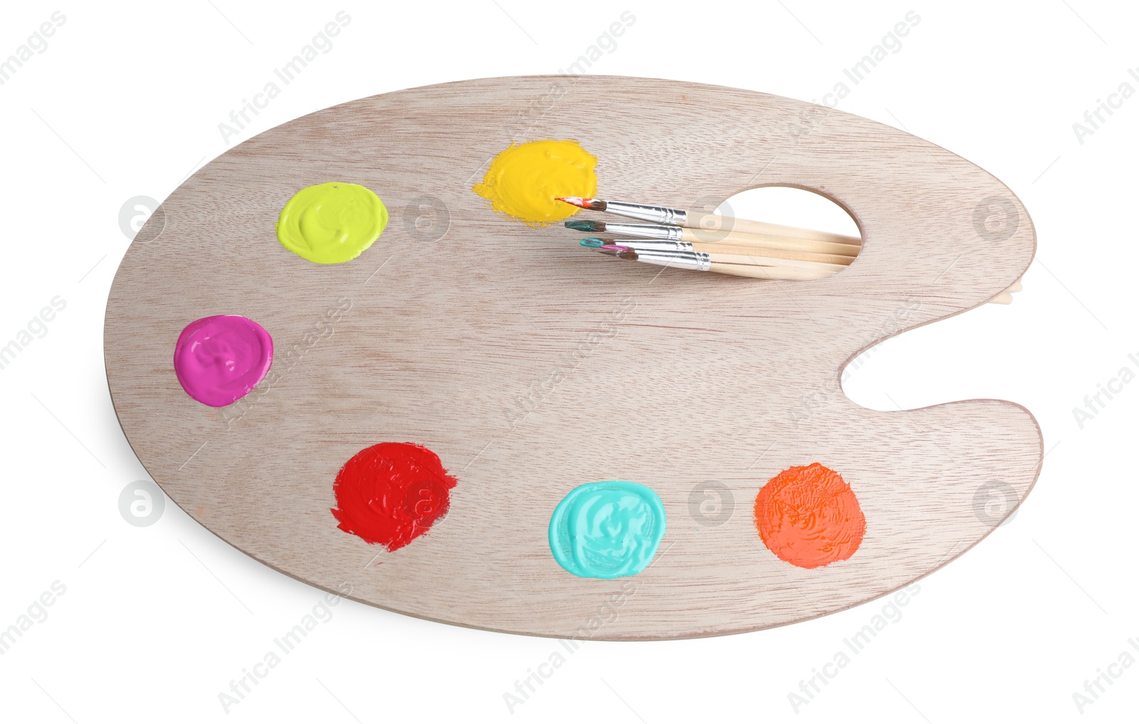 Photo of Wooden artist's palette with samples of paints and brushes isolated on white