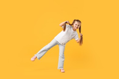 Photo of Cute little girl dancing on yellow background