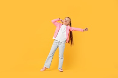Cute little girl dancing on yellow background