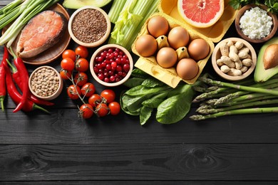 Photo of Many different healthy food on black wooden table, flat lay. Space for text