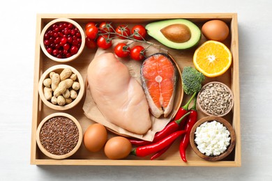 Tray with many different healthy food on white table, top view