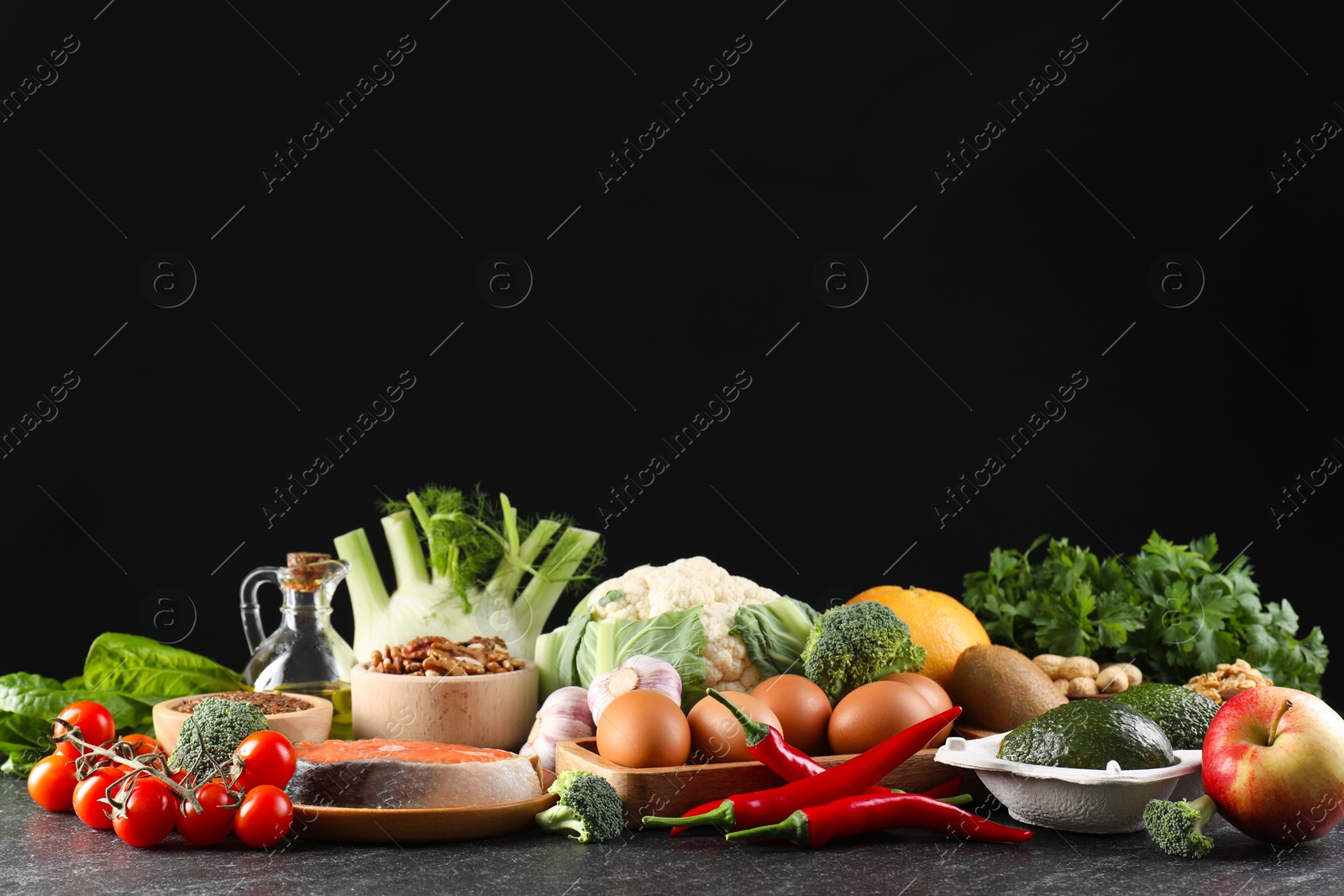 Photo of Many different healthy food on dark textured table against black background. Space for text