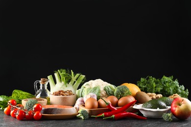 Many different healthy food on dark textured table against black background. Space for text