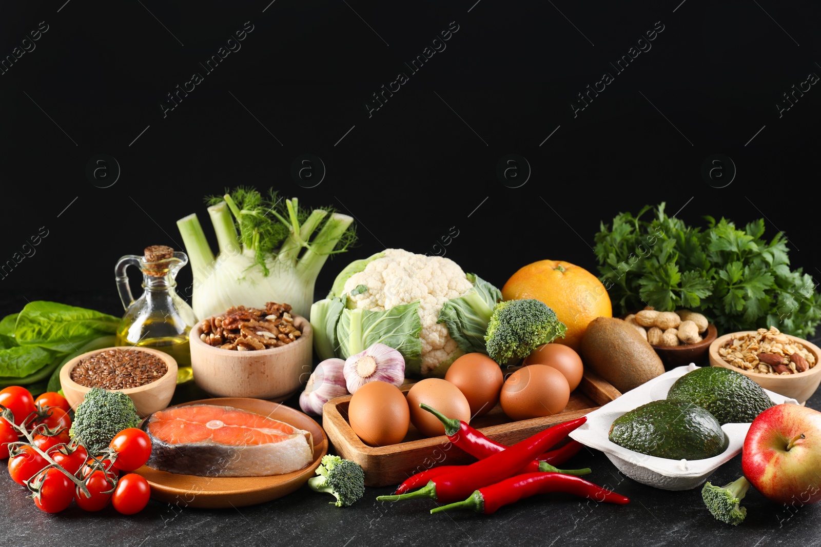 Photo of Many different healthy food on dark textured table against black background. Space for text