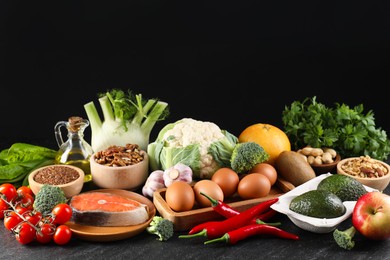 Photo of Many different healthy food on dark textured table against black background. Space for text