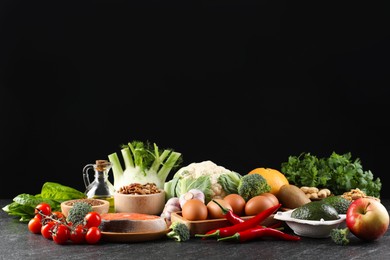 Photo of Many different healthy food on dark textured table against black background. Space for text