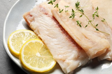 Photo of Plate with raw cod fish, microgreens and lemon on table, closeup