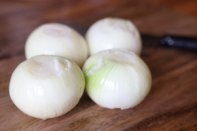 Photo of Fresh ripe onion bulbs on wooden table, closeup