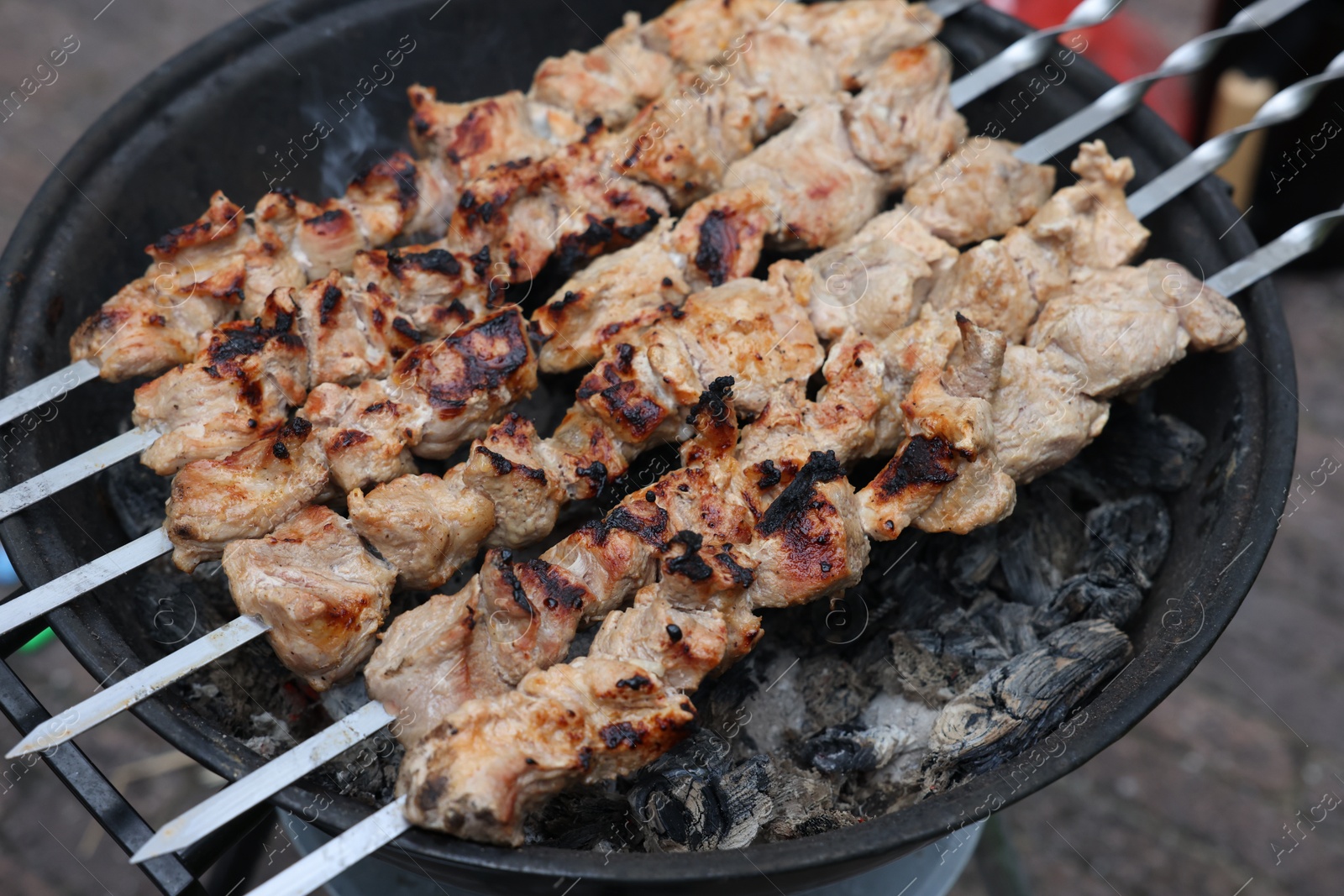 Photo of Cooking delicious kebab on metal brazier outdoors, above view