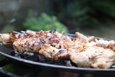 Photo of Cooking delicious kebab on metal brazier outdoors, closeup