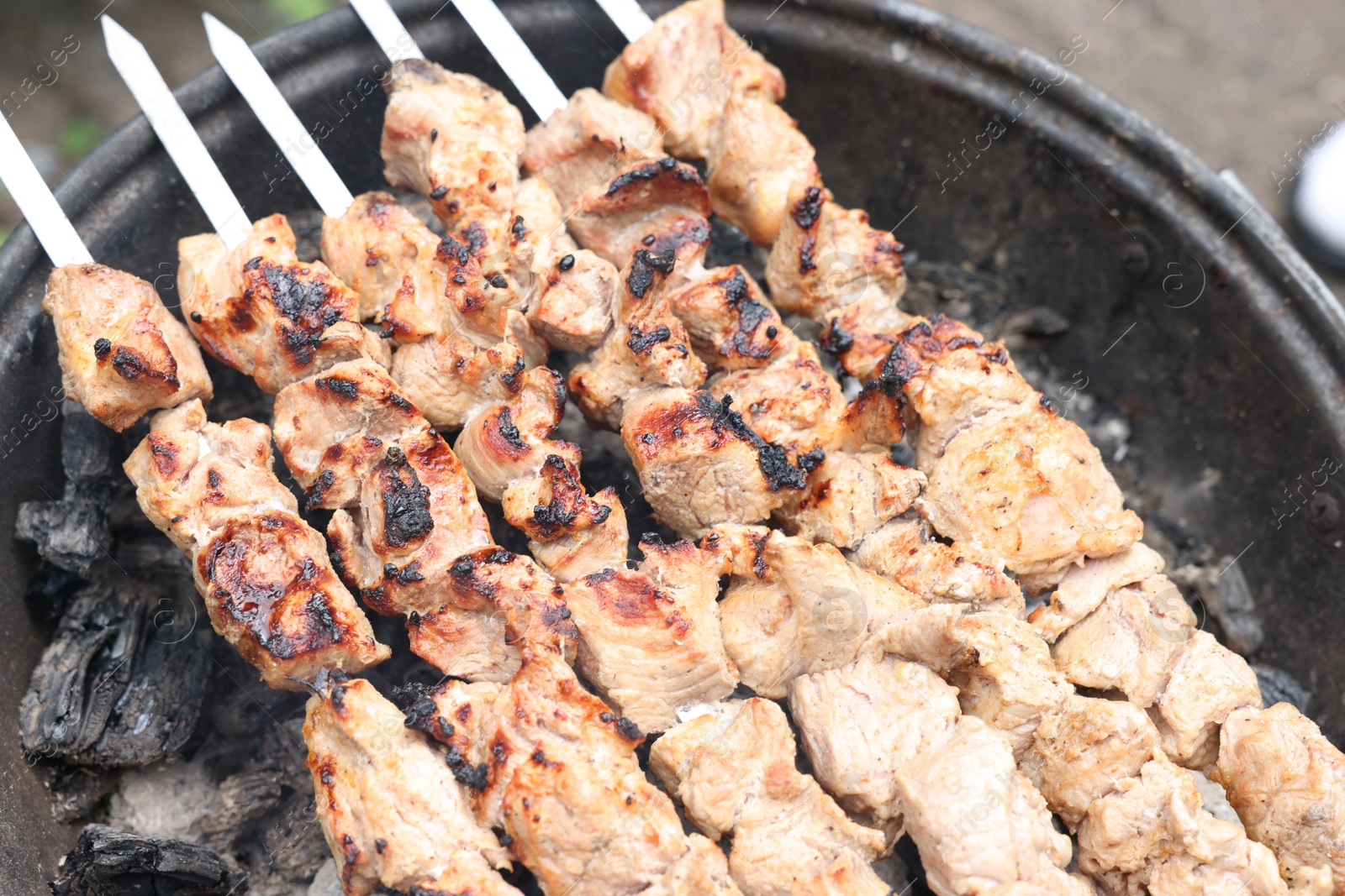 Photo of Cooking delicious kebab on metal brazier outdoors, above view