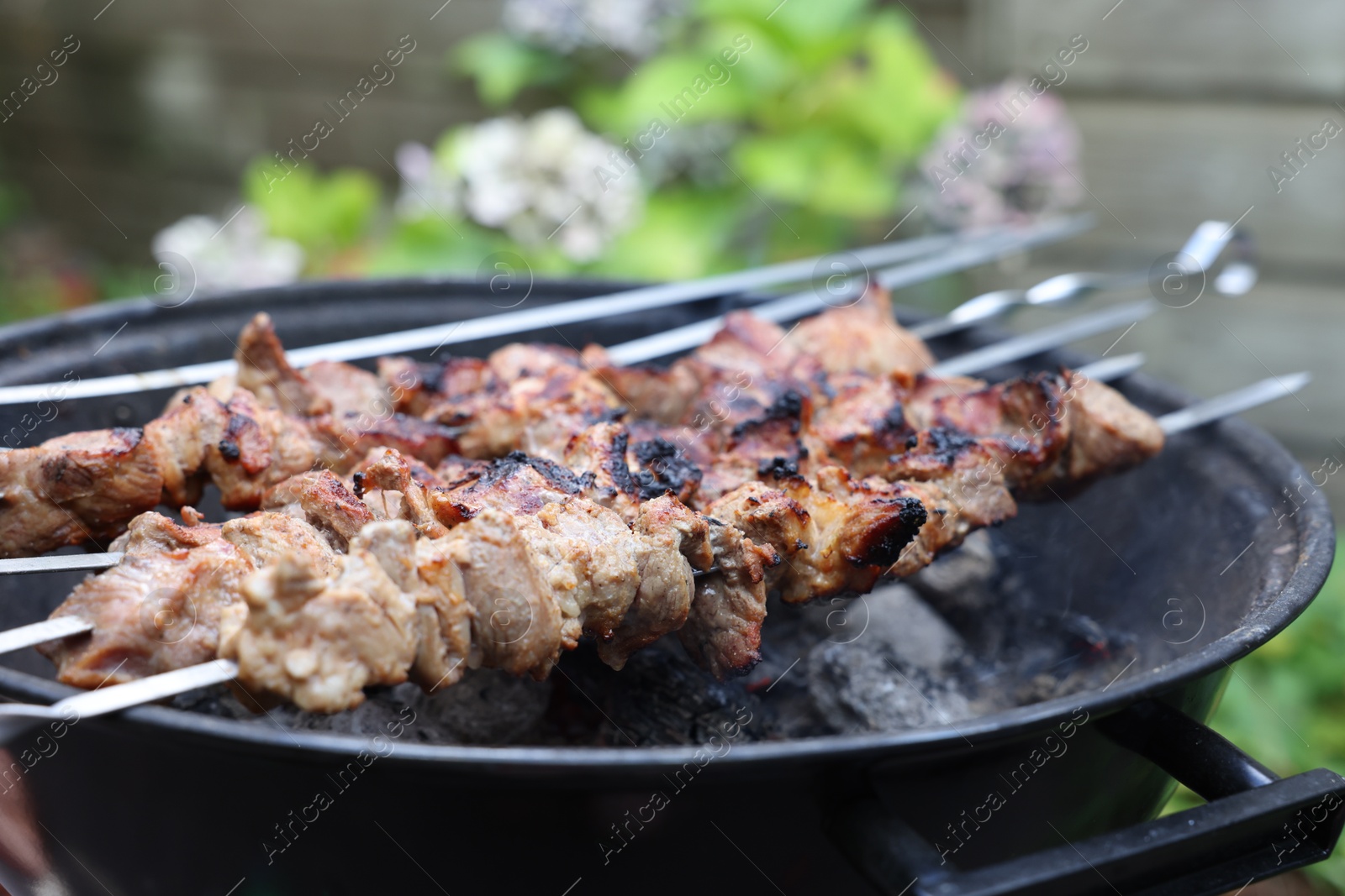 Photo of Cooking delicious kebab on metal brazier outdoors, closeup