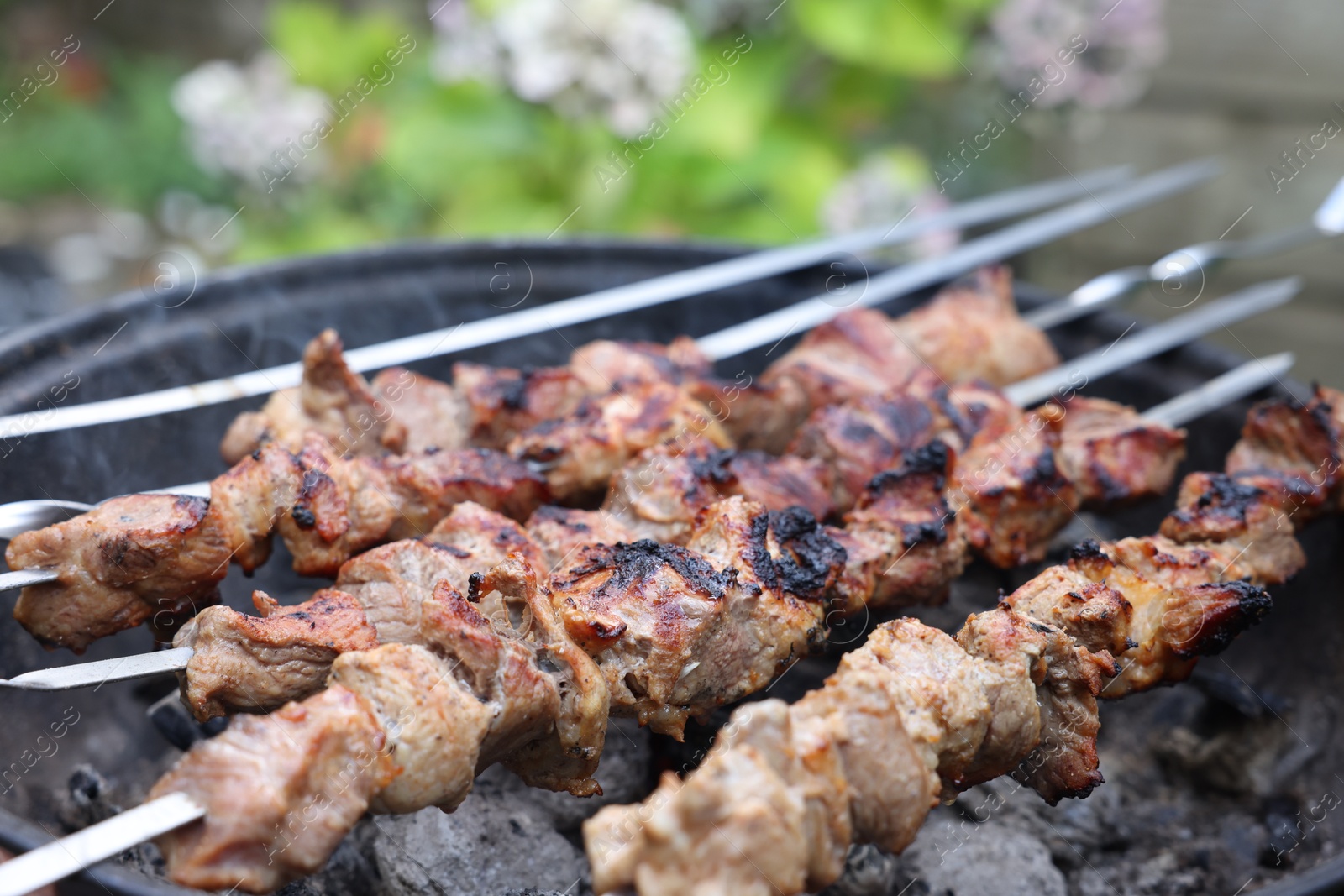 Photo of Cooking delicious kebab on metal brazier outdoors, closeup