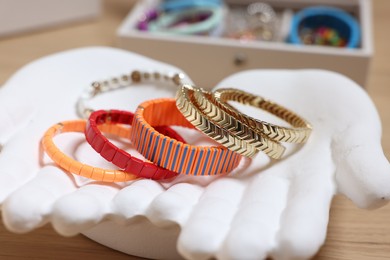 Photo of Ceramic hand stand with many different bracelets on table, closeup