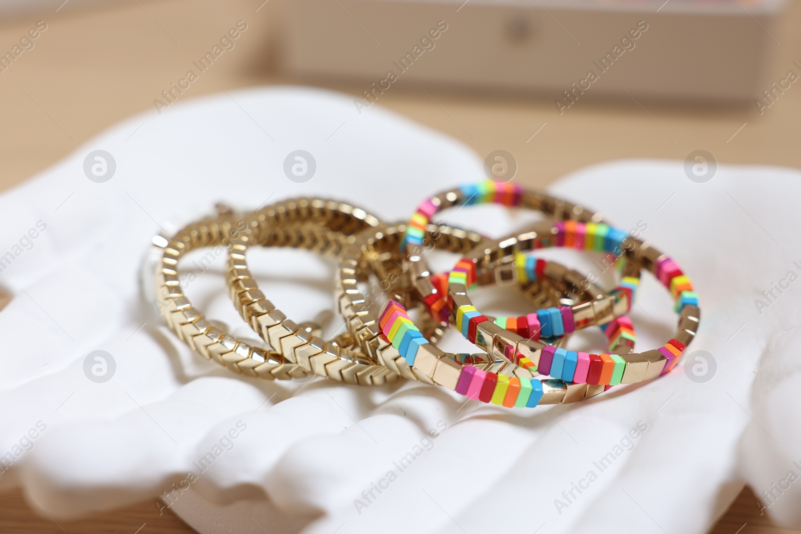 Photo of Ceramic hand stand with many different bracelets on table, closeup