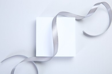 Beautiful grey ribbon and gift box on white background, top view