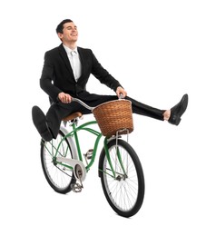 Smiling man having fun while riding bicycle with basket on white background