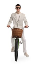 Smiling man in sunglasses riding bicycle with basket on white background