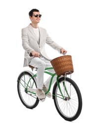 Smiling man in sunglasses riding bicycle with basket on white background