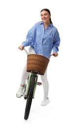 Smiling woman riding bicycle with basket on white background