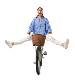 Emotional woman having fun while riding bicycle with basket against white background