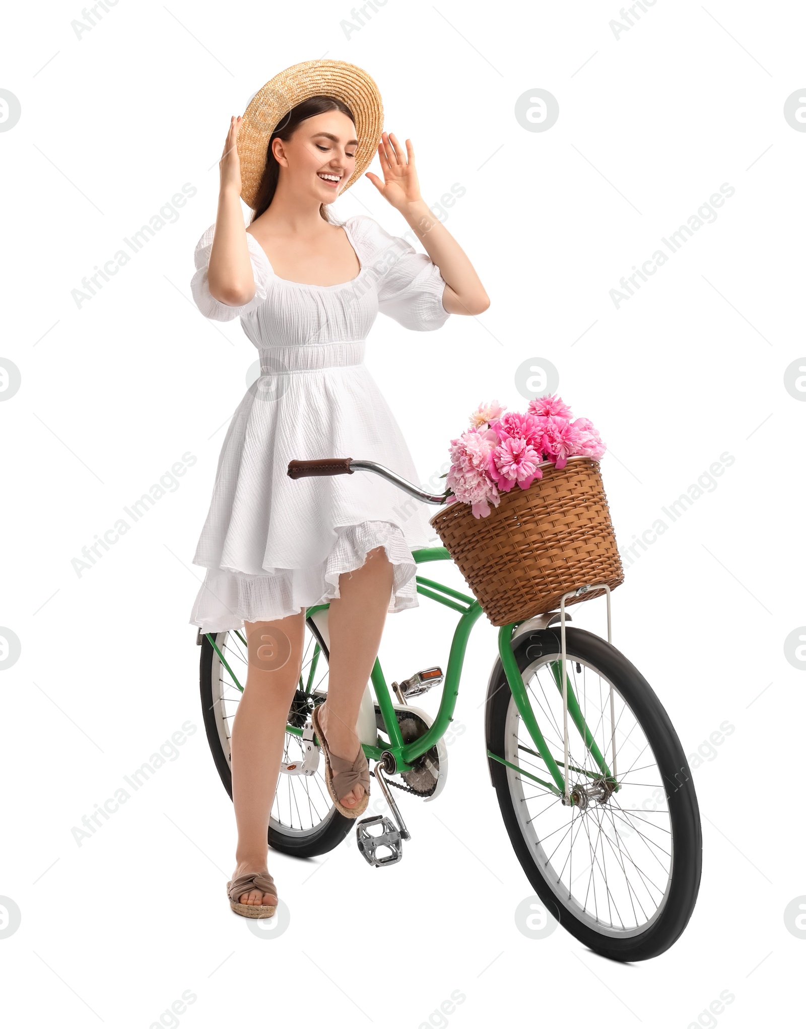 Photo of Smiling woman on bicycle with basket of peony flowers against white background