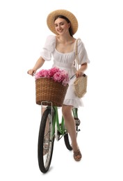 Smiling woman riding bicycle with basket of peony flowers on white background