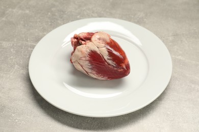 Raw heart and plate on grey table