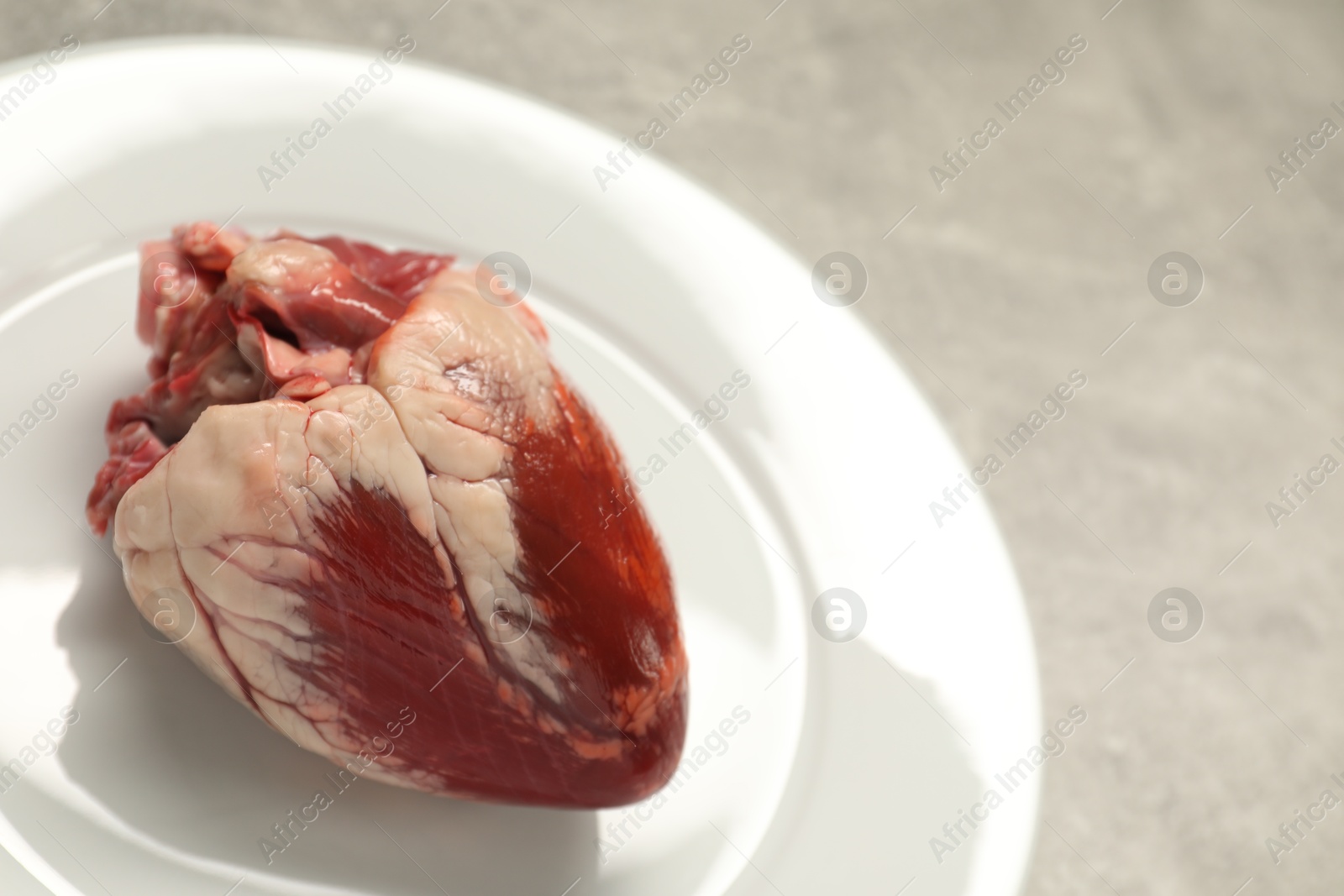 Photo of Raw heart on grey table, closeup view