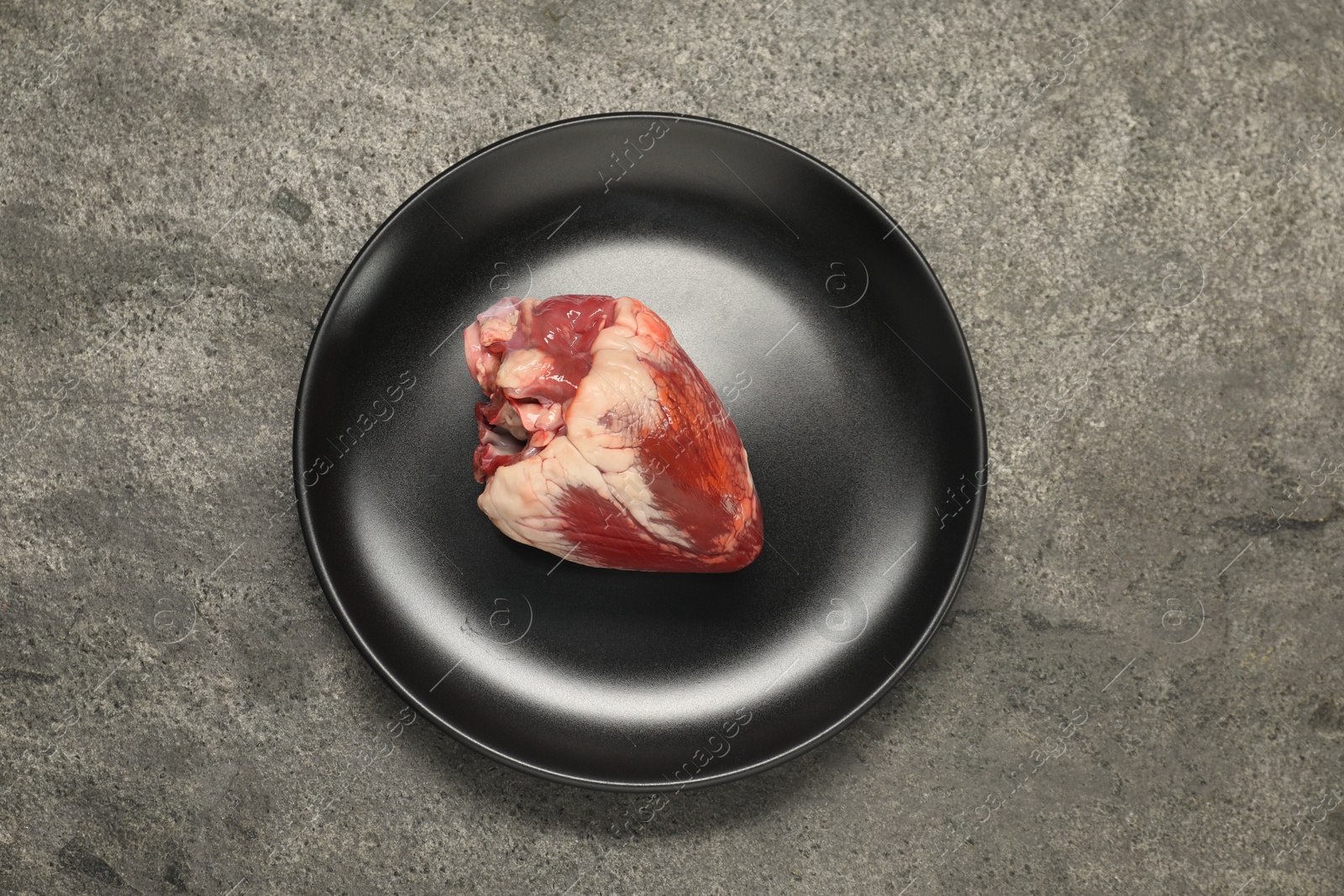 Photo of Raw heart on grey table, top view