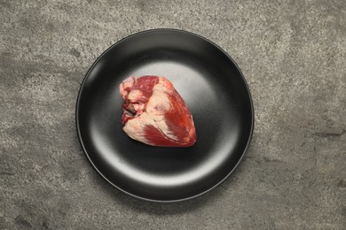 Raw heart on grey table, top view