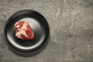 Raw heart on grey table, top view. Space for text