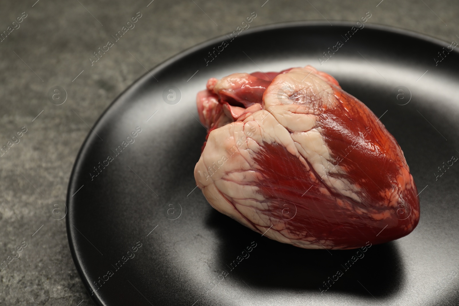 Photo of Raw heart on grey table, closeup view