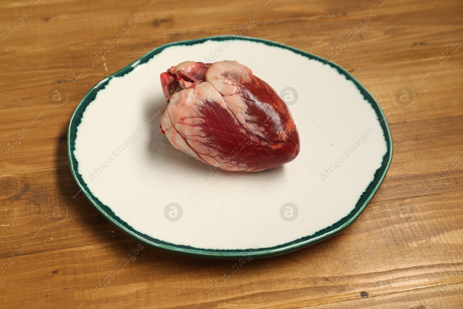 Photo of Raw heart and plate on wooden table