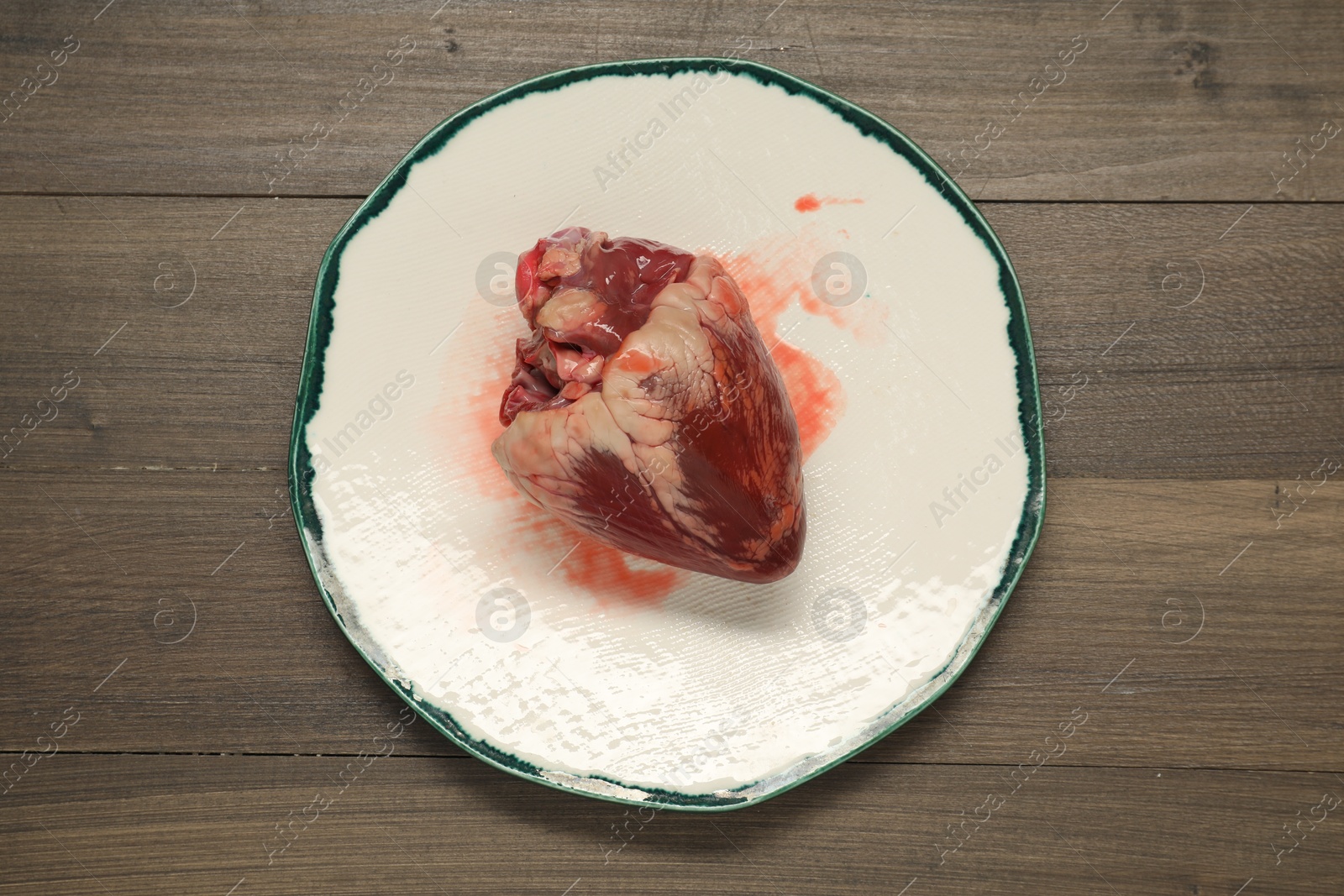 Photo of Raw pork heart on wooden table, top view