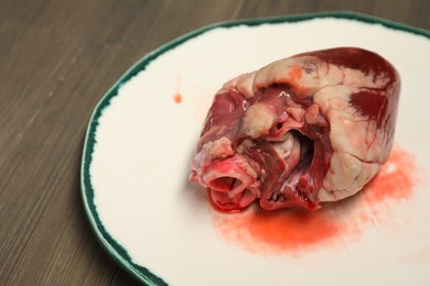 Photo of One raw pork heart on wooden table