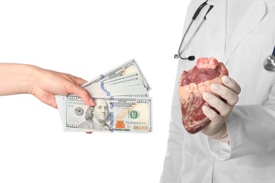 Photo of Patient giving dollar banknotes to doctor with heart on white background, closeup