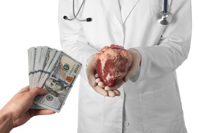 Patient giving dollar banknotes to doctor with heart on white background, closeup