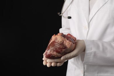 Photo of Doctor with heart on black background, closeup. Space for text