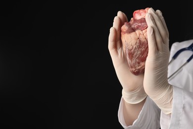 Photo of Doctor with heart on black background, closeup. Space for text